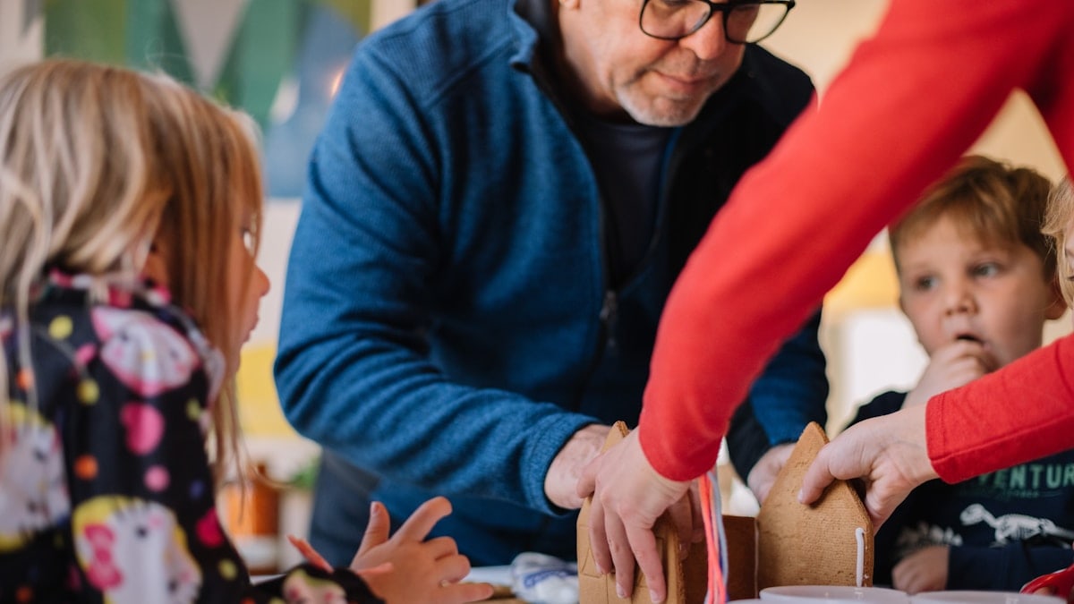 kids with grandparents making a gingerbread house